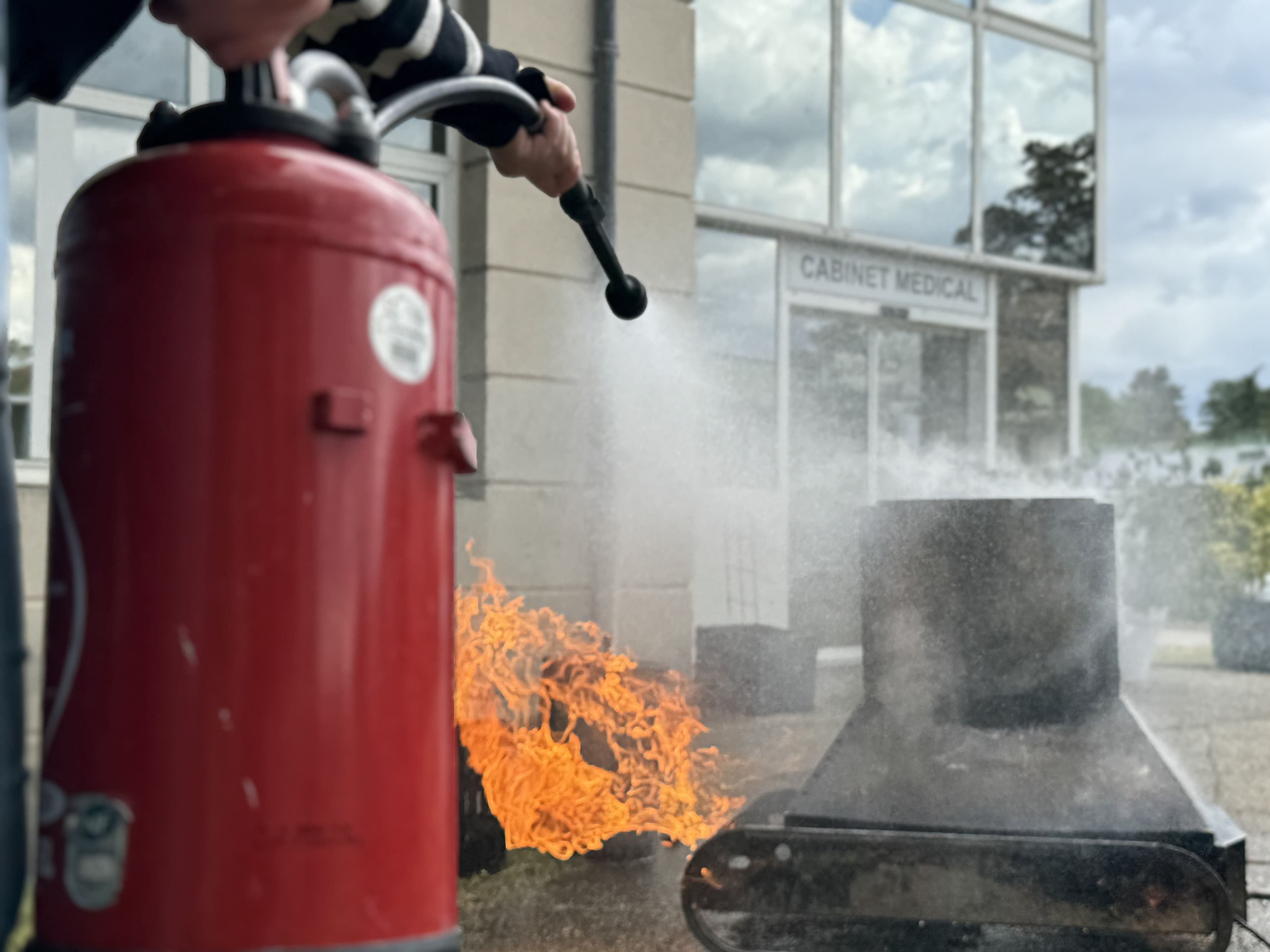 Technicien Vériflamme vérifiant un extincteur sur un bac à flamme